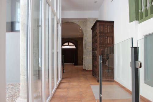 Moderno pasillo en apartamento Palacio Mambrilla, Valladolid con suelos de madera y divisiones de cristal
