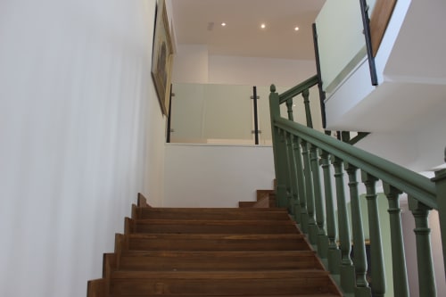 Escalera moderna con barandillas verdes en el hotel Palacio Mambrilla de Valladolid, con peldaños de madera e interior luminoso