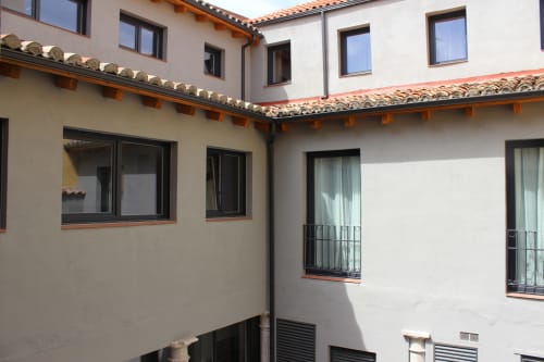 Vista del patio del hotel apartamento Palacio Mambrilla en Valladolid con tejado de barro, paredes blancas y ventanas con marcos negros
