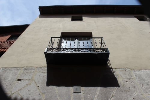 Balcón de hierro forjado ornamental en la fachada color crema del hotel apartamentos Palacio Mambrilla en Valladolid