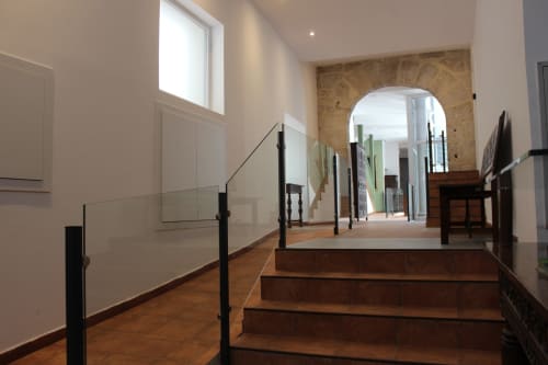 Escalera moderna en el hotel Palacio Mambrilla de Valladolid, con barandillas de cristal, escalones de madera y acceso a pasillo abovedado