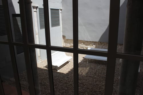Vista a través de ventana con marco negro del patio del Palacio Mambrilla en Valladolid, con suelo de grava y unidades de ventilación blancas