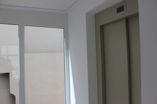 Moderno pasillo con puertas de ascensor y vistas a la ciudad en Palacio Mambrilla, Valladolid