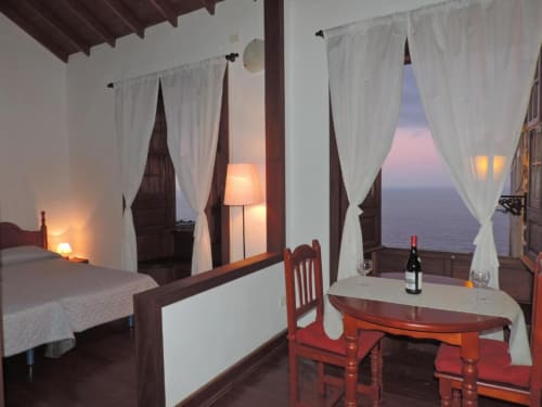 Estudio en Casa Rural Los Helechos, Agulo: comedor, vistas al océano al atardecer y mobiliario de madera oscura
