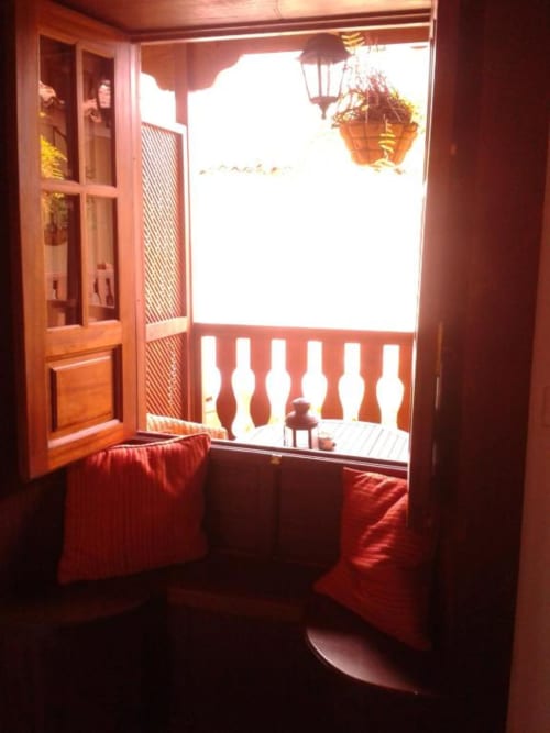 Puertas de madera abriéndose a un soleado balcón con barandillas blancas que dan al patio de Casa Rural Los Helechos en Agulo