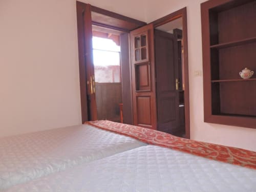 Dormitorio espacioso en apartamento Casa Rural Los Helechos con puertas de madera, estanterías y luz natural desde el balcón en Agulo