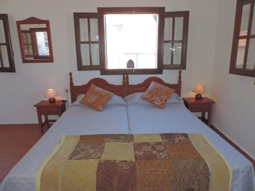 Habitación en Casa Rural Los Helechos con cama de madera, vistas al océano, mesitas de noche con lámparas y ropa de cama estampada