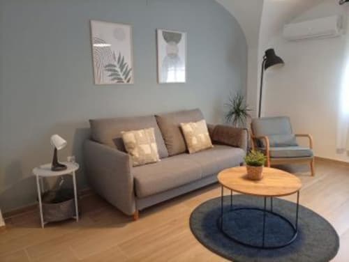 Salón moderno en apartamento de Cáceres con sofá gris, mesa de madera y decoración contemporánea con vistas a Plaza Mayor