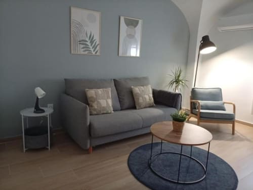 Moderna sala de estar con sofá gris, mesa de centro de madera y arte contemporáneo en hotel de Cáceres