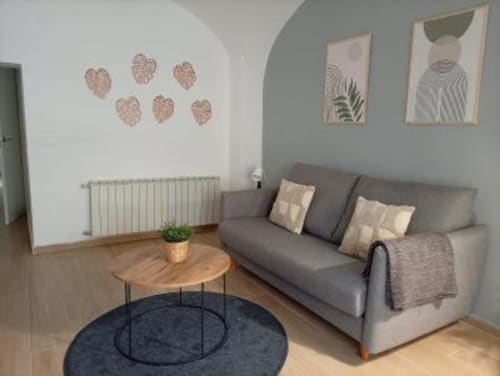 Moderno salón de apartamento en Cáceres con sofá gris, mesita de madera, arte mural abstracto y radiador