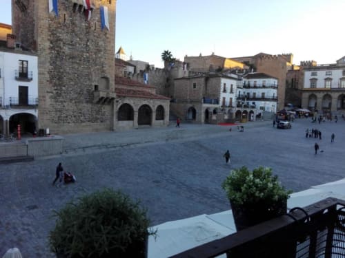 Vista de la Plaza Mayor de Cáceres desde el balcón de Apartamentos La Machacona con edificios históricos de piedra y patio