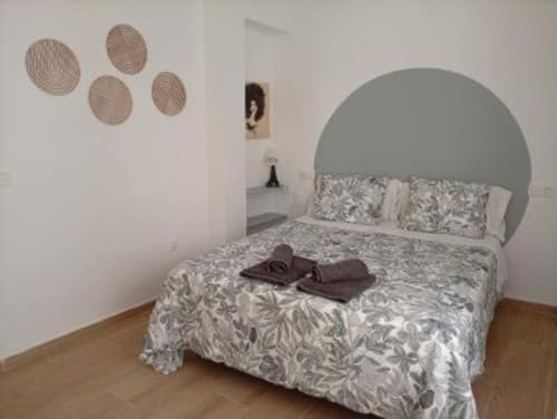 Habitación moderna en Apartamentos La Machacona de Cáceres con cabecero circular, ropa de cama estampada y pared decorativa