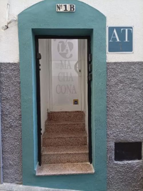 Entrada a Apartamentos La Machacona, Cáceres: puerta turquesa nº 1B con escaleras y acceso privado