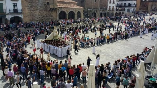 Plaza Mayor de Cáceres durante procesión religiosa con multitudes y edificios históricos, vista desde balcón de apartamento