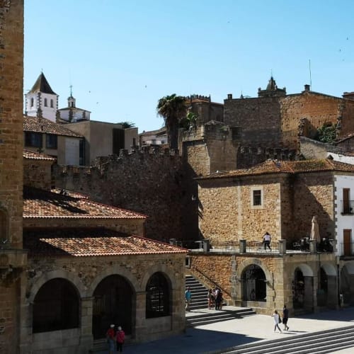 Plaza Mayor histórica de Cáceres con edificios de piedra, arcos y torre de iglesia al fondo