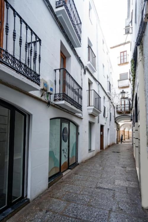Estrecha calle empedrada con edificios encalados y balcones de hierro forjado en la histórica Cáceres, España
