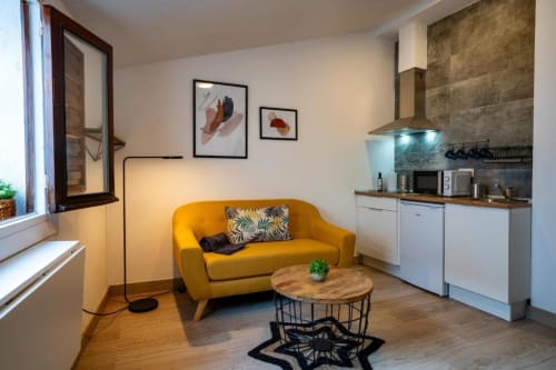 Moderno apartamento de 1 dormitorio en Cáceres con sofá amarillo, cocina pequeña y muebles de madera