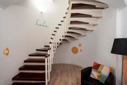 Escalera moderna con escalones de madera oscura en apartamento de La Machacona, Cáceres, con sofá y arte mural