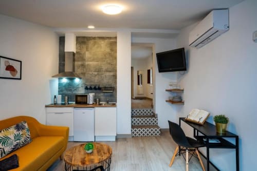 Apartamento moderno de 1 dormitorio en Cáceres con salón abierto, cocina americana, sofá, escritorio y TV de pared