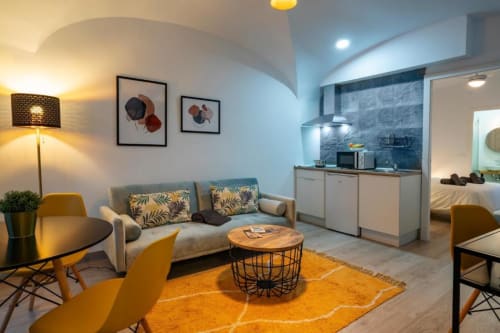 Moderno salón de apartamento de 1 dormitorio en Cáceres con sofá, cocina americana, detalles amarillos y muebles contemporáneos