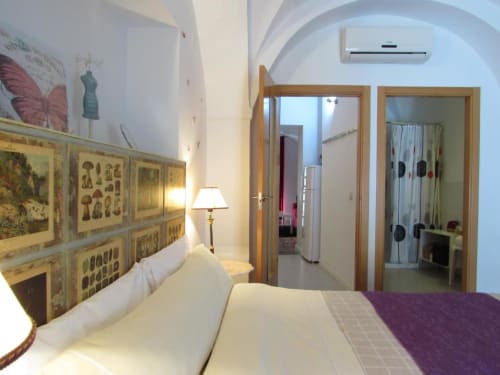 Dormitorio moderno en apartamento de Cáceres con cabecero decorativo, camas gemelas, puertas de madera, aire acondicionado y acceso a galería