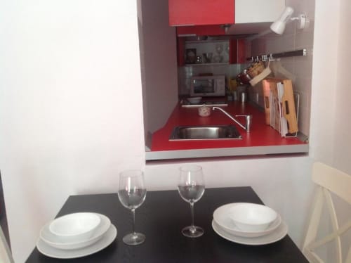 Moderna kitchenette con muebles rojos y zona de comedor en Apartamentos La Machacona en Cáceres