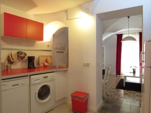 Cocina moderna con armarios rojos y electrodomésticos blancos en planta baja de Apartamentos La Machacona, Cáceres España