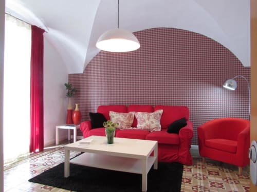 Moderna sala de estar en apartamento de Cáceres con sofá rojo, pared con patrón y muebles contemporáneos