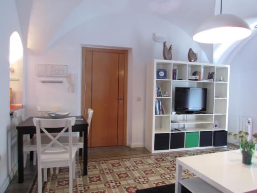 Sala de estar de apartamento en planta baja en Cáceres con estanterías blancas, TV de pantalla plana, comedor y azulejos ornamentales