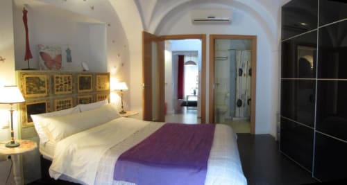 Dormitorio moderno en Apartamentos La Machacona de Cáceres con cama queen, manta morada, cabecero de madera, techo abovedado y