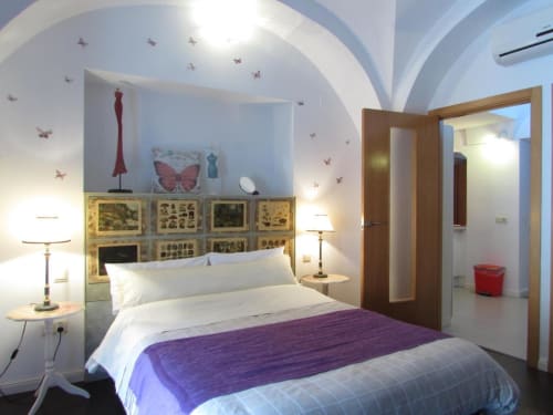 Dormitorio moderno en Apartamentos La Machacona con techo abovedado, ropa de cama púrpura y decoración de mariposas en la pared