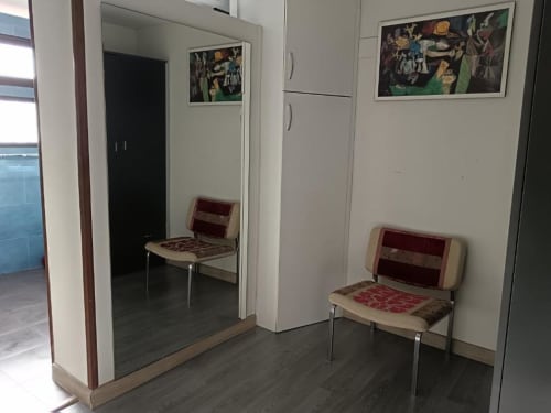 Zona de espera en Apartamentos La Machacona, Cáceres, con dos sillas y cuadros enmarcados en paredes blancas