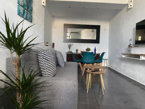Sala de estar de apartamento moderno de 1 dormitorio en Cáceres con sillas turquesas, sofá gris, mesa de comedor y diseño contemporáneo