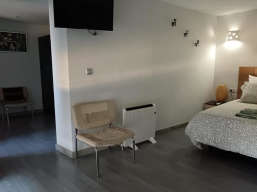 Habitación moderna de Apartamentos La Machacona con cama, silla, calefactor, televisor y decoración minimalista en España
