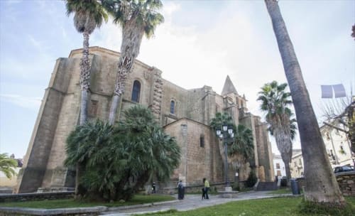 Iglesia de piedra histórica con palmeras en Cáceres, España cerca de Apartamentos La Machacona