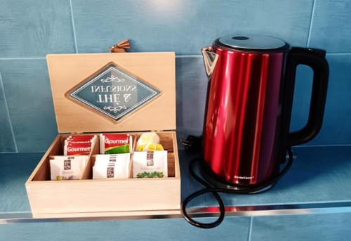 Hervidor eléctrico rojo y caja de regalo de té con selecciones gourmet en la cocina de un apartamento en Cáceres