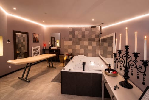 Suite spa luxueuse avec bain à remous chauffé, éclairage ambiant, table de massage et décoration élégante aux Secrets de Winna