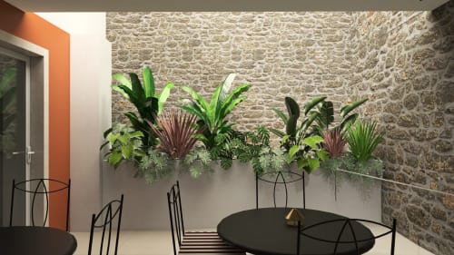 Modern courtyard seating area at Feel Sintra with lush green plants, stone walls, black metal chairs and tables, orange