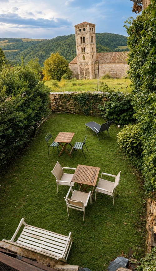 Jardín de Casa Tapiolas con zonas de descanso con vistas a la torre de la iglesia medieval en Molló, Girona