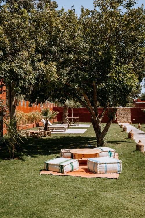 Cour de l'Eucalyptus Ethnic Hotel à Essaouira avec coussins de sol, arbres matures et murs en terre cuite