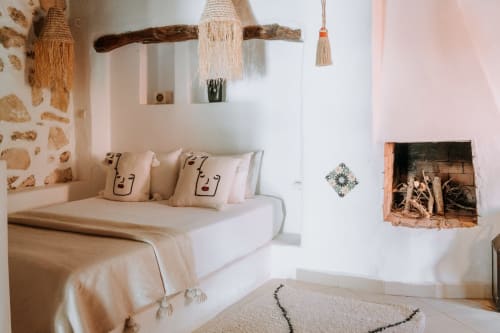 Chambre minimaliste à l'hôtel Eucalyptus Ethnic à Essaouira avec lit blanc, tentures macramé tissées et bois rustique