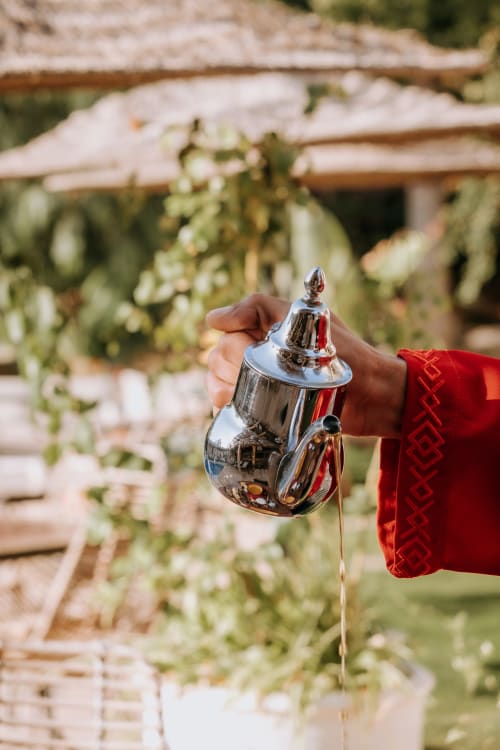 Main versant l'eau d'une théière marocaine ornée à l'hôtel Eucalyptus Ethnic à Essaouira