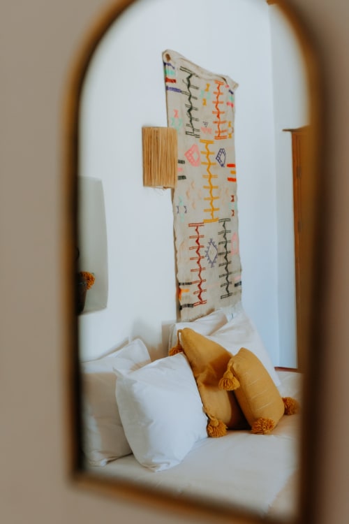 Coin chambre douillet à l'hôtel Eucalyptus Ethnic à Essaouira avec coussins décoratifs et art mural tissé coloré