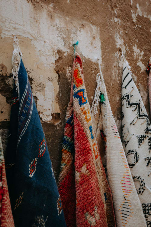 Textiles marocains colorés tissés à la main suspendus sur un mur patiné à l'hôtel Eucalyptus Ethnic, Essaouira