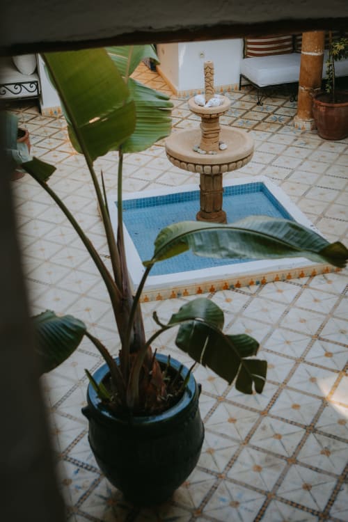 Cour de l'hôtel Eucalyptus Ethnic à Essaouira avec fontaine marocaine traditionnelle, carrelage au sol et plantes en pots