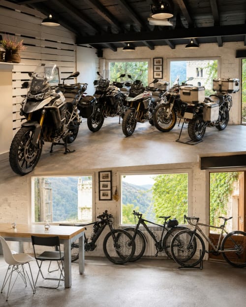 Garaje de aventura Casa Tapiolas en Molló exhibiendo motocicletas y bicicletas con vistas a las montañas