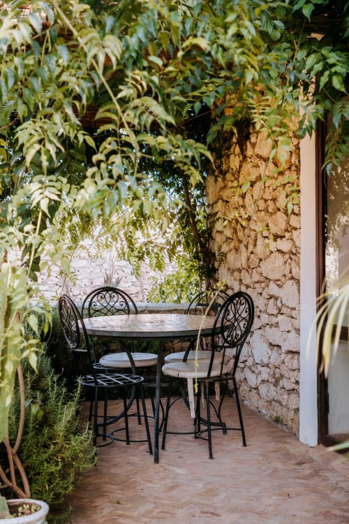 Cour intimiste avec mobilier en fer forgé de l'hôtel Eucalyptus Ethnic à Essaouira, entourée de verdure luxuriante