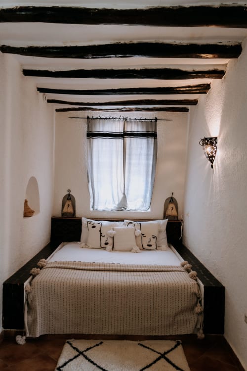 Acogedora habitación bereber en el hotel Eucalyptus Ethnic de Essaouira con vigas de madera vista, paredes blancas y decoración tradicional