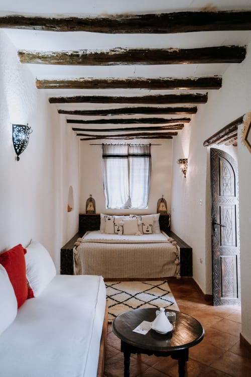 Chambre d'hôtel Eucalyptus de style ethnique avec plafond à poutres en bois rustique, murs blancs, décoration berbère traditionnelle et fenêtre