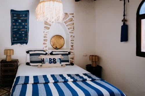 Acogedora habitación bereber en el hotel Eucalyptus Ethnic de Essaouira con ropa de cama a rayas azul marino, decoración tradicional y artesanía